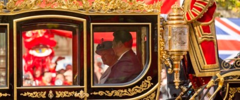 Chinese President Xi Jinping, right, sits beside Britain's Queen Elizabeth II, in a horse-drawn carriage passing a large Chinese flag on the route along the Mall to Buckingham Palace in London, Tuesday, Oct. 20, 2015. Chinese President Xi Jinping prepared to address Britain's Parliament and dine with Queen Elizabeth II Tuesday as he began a state visit that is intended to cement close economic ties between the two countries  but risks being overshadowed by concerns over Beijing's growing economic clout in Britain. (AP Photo/Matt Dunham)